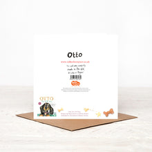 Load image into Gallery viewer, Christmas card stood on matching brown envelope, showing the reverse side of Otto Dachshund Christmas card featuring details of tie-in book &#39;Otto The TOP Dog&#39; and Christmas charity partner Read for Good. 