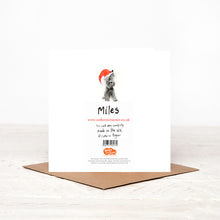 Load image into Gallery viewer, Illustrated scottie dog Christmas card stood on matching brown envelope showing reverse side, featuring details of Christmas charity partner, children&#39;s literacy charity, Read for Good. 