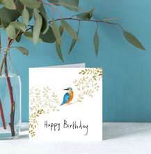 Load image into Gallery viewer, Greeting card with a bird illustration and 'Happy Birthday' text, placed on a surface with a vase of greenery against a blue wall.