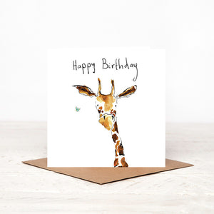 A white square greetings card featuring a watercolour illustration of a giraffe, with a handwritten 'Happy Birthday' message,  stood up on a matching brown craft envelope.