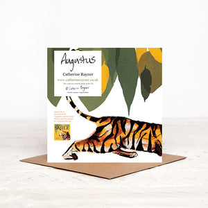 Reverse of square tiger birthday card, showing wraparound watercolour illustration of tiger and green leaves., stood on matching brown envelope.