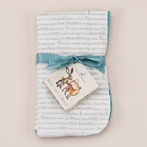 Storytime dribble cloths laid flat with ribbon and storybook label