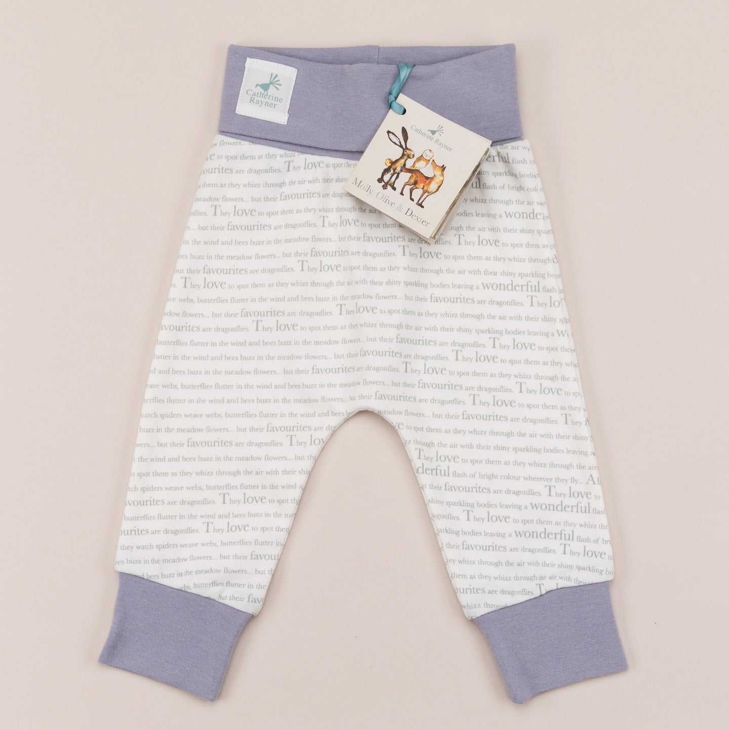 Unisex joggers for babies aged 0-2 years with exclusive Storytime print and  dusky heather trim, laid flat on a cream background.