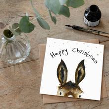 Load image into Gallery viewer, Christmas card featuring illustration of Trevor the Christmas Donkey laid flat on a wooden table with a matching brown envelope. 