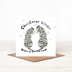 greeting card featuring a white tiger couple smiling at each other and "Christmas kisses" text above them