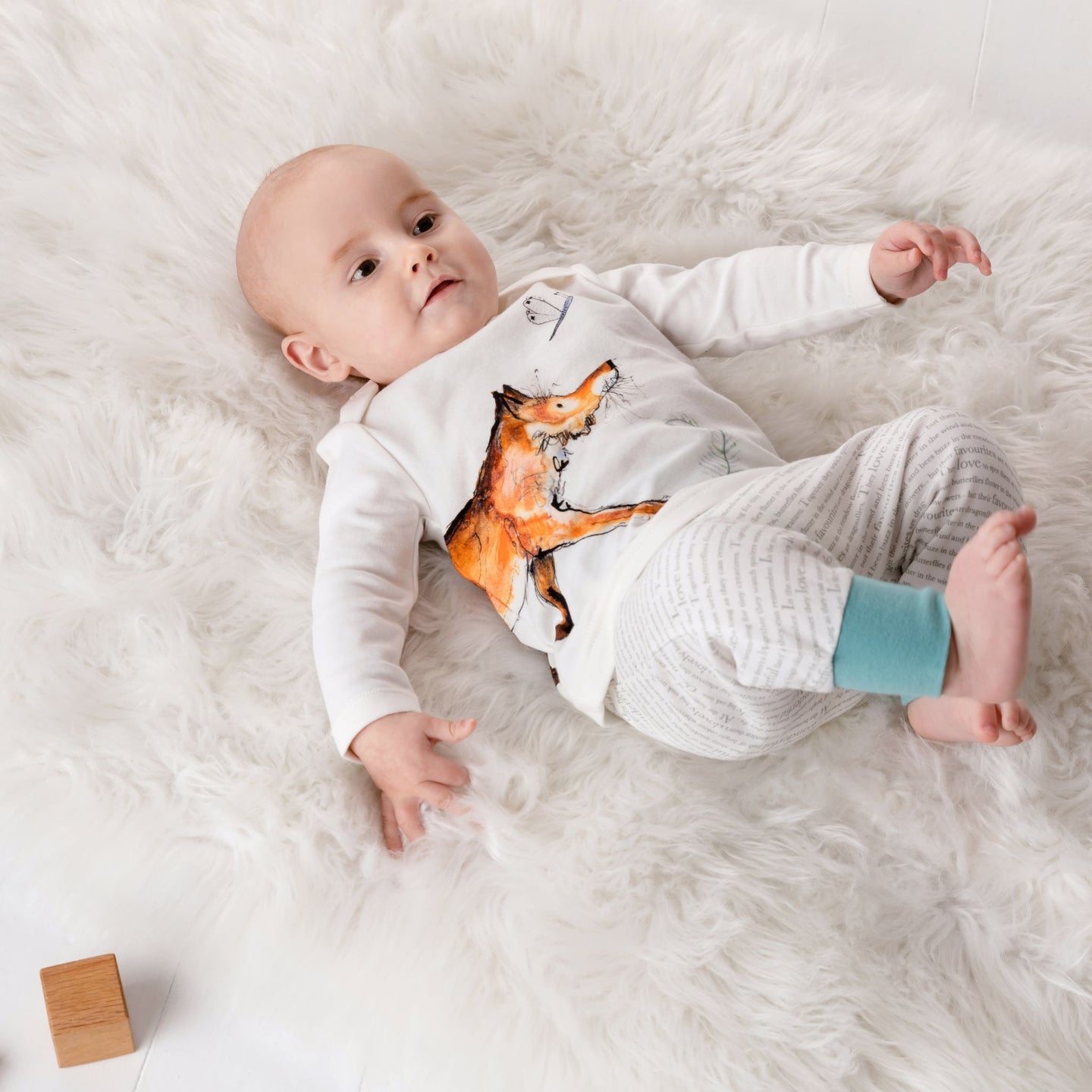 One year old baby lying down wearing the illustrated Dexter fox top and matching storytime joggers with ocean blue cuffs.
