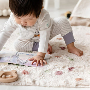 Toddler wearing dusky heather storytime joggers, reading Smelly Louie by Catherine Rayner