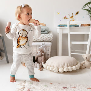 Blonde toddler stood up wearing ocean blue storytime joggers and the olive owl  print top as she plays. 