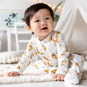 Young toddler smiling sat forward wearing Olive Owl print babygrow