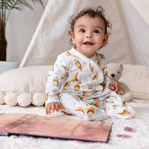 6 month old baby looking up smiling, wearing Olive Owl babygrow