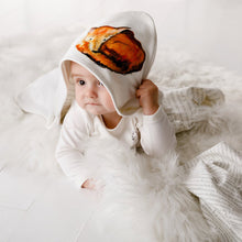 Load image into Gallery viewer, Six month old baby wearing Dexter hooded blanket lying on the floor,