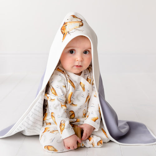Six month old baby, sat up wearing Olive owl hooded blanket and Olive owl babygrow
